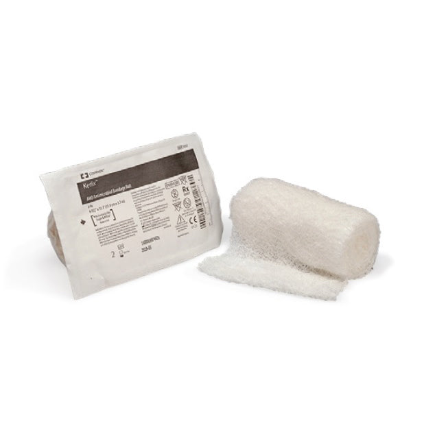 A rolled Kerlix Anti-embolic bandage rests on a white surface next to its packaging. The packaging includes product details and symbols.