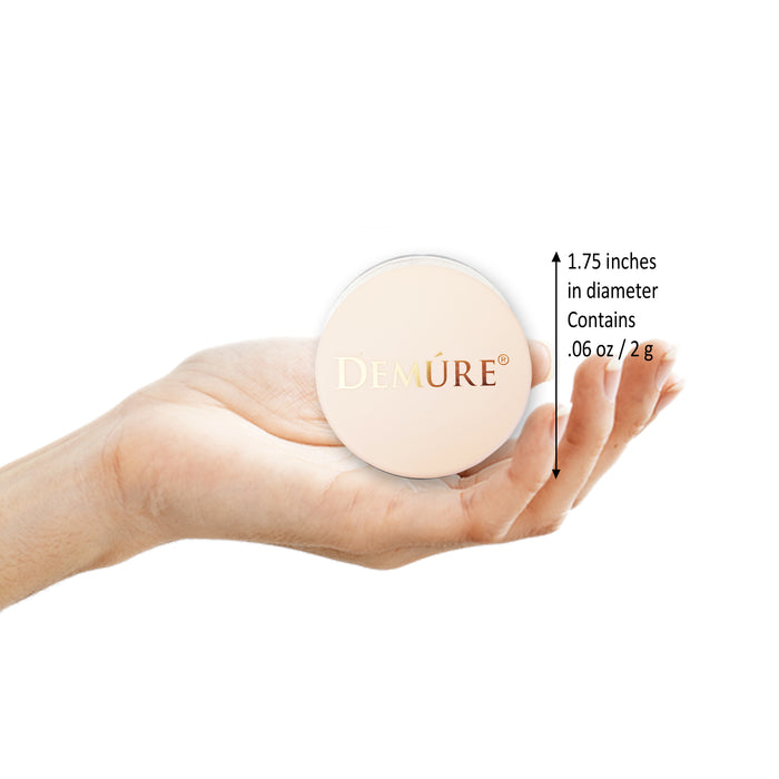 Hand holding a Demure Concealer with measurements on a white background