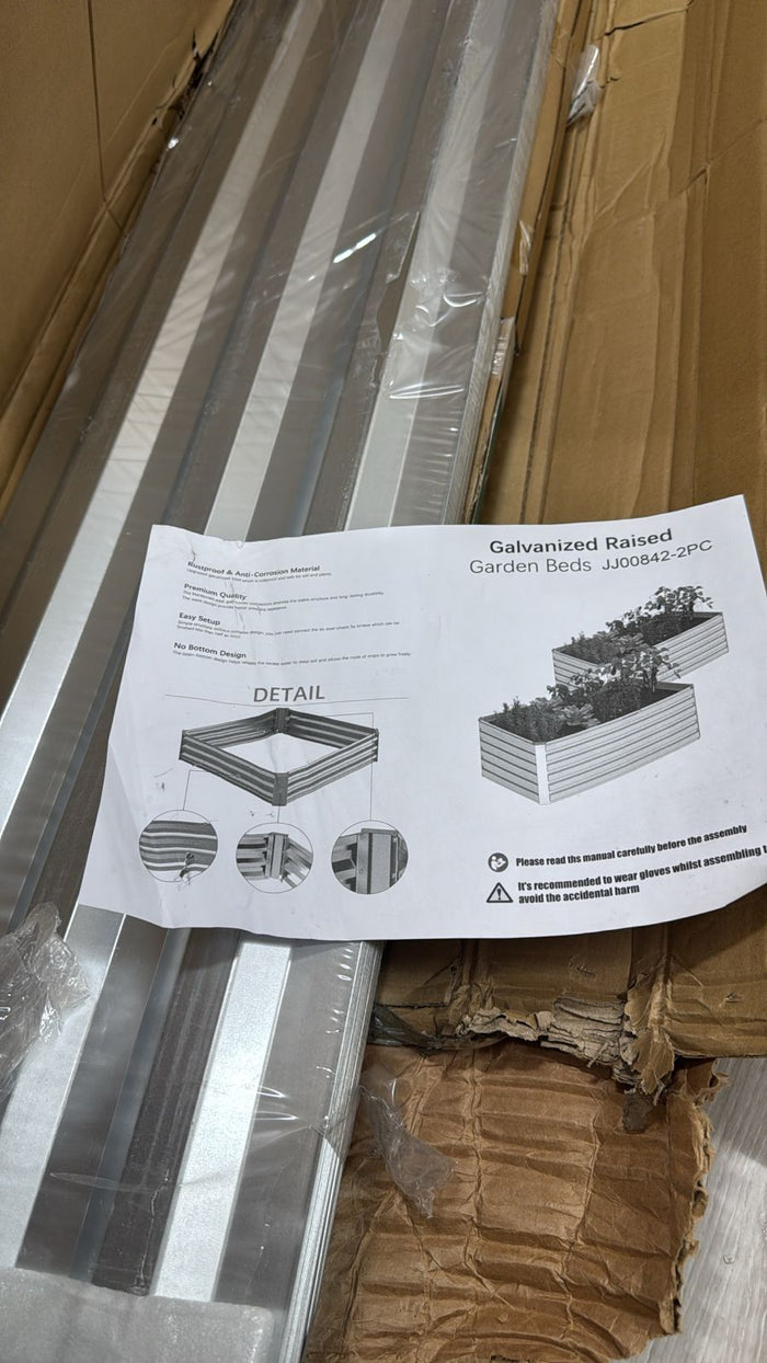 Metal garden bed with packaging and instructions on a cardboard surface
