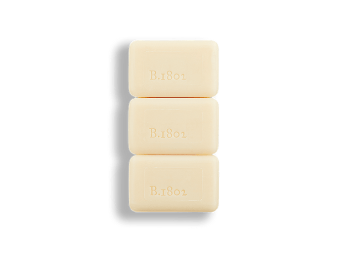 An image of 3 unwrapped beekman 1802 3.5 oz sunshine lemon travel sized bar soap.