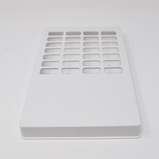 A white rectangular plate with numerous rectangular cutouts sits on a white surface.