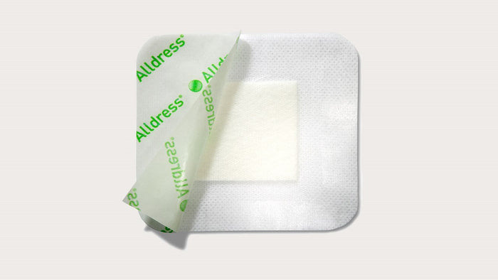 A square adhesive bandage, partially peeled, reveals a white absorbent pad; it is displayed against a plain light-grey background.