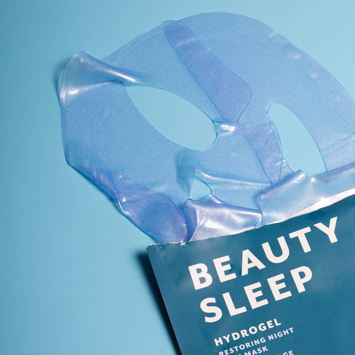 Beauty Sleep blue hydrogel mask lifted from packaging on a blue background.