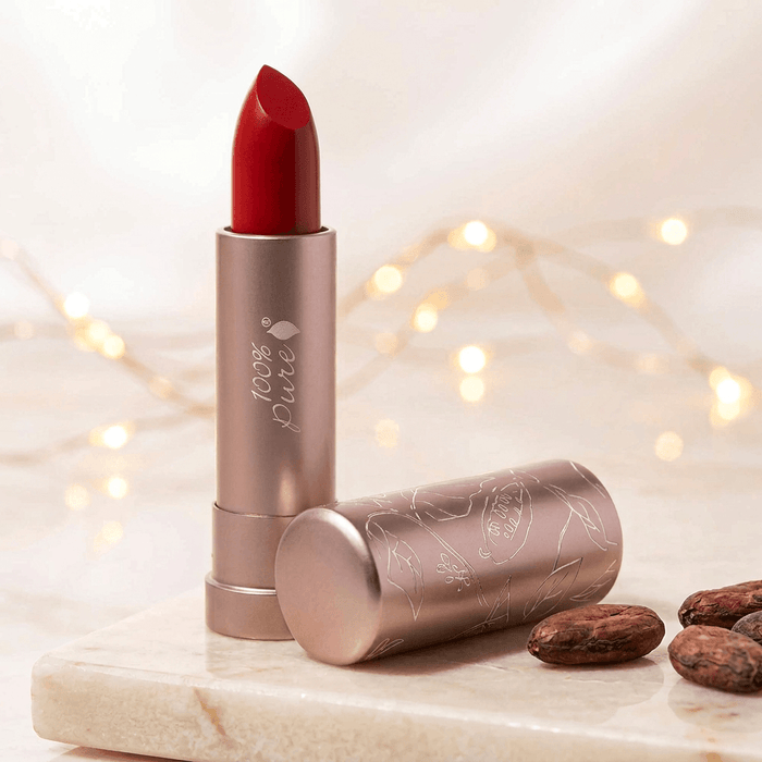 Red lipstick with a beige case on a marble surface with lights in the background