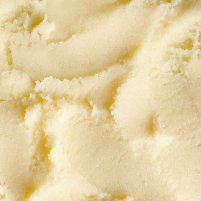 Close-up texture of creamy, whipped body scrub with a smooth, buttery consistency and soft sheen.