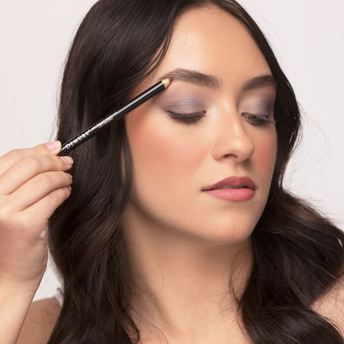 Woman applying Demure Medium Brown Brow Liner to her brows, looking down.