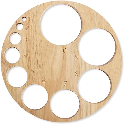 A circular wooden board displays various sized circular cutouts, arranged asymmetrically across its surface.