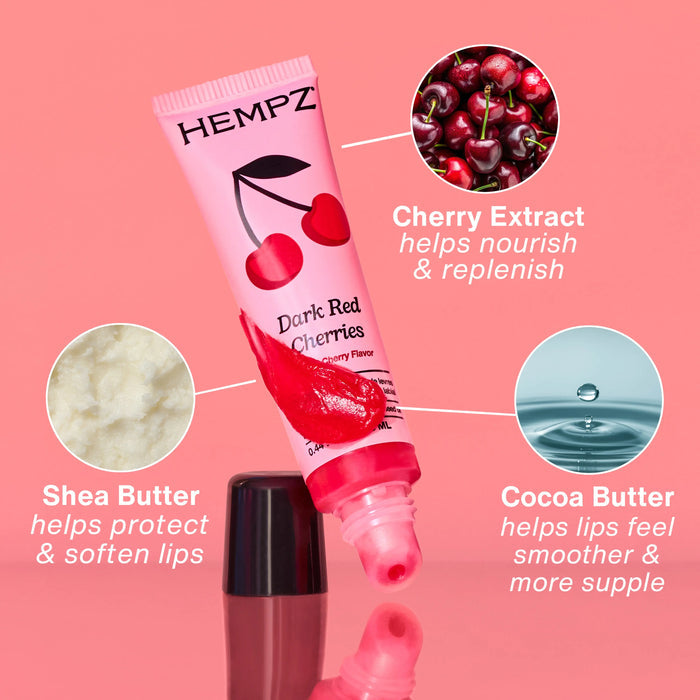 Hempz Dark Red Cherries lip balm tube with cherry extract, shea butter, and cocoa butter benefits on a pink background.
