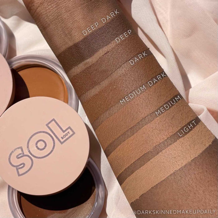 ColourPop SOL Face & Body Bronzing Balm in Deep swatched on a forearm next to Light, Medium, Medium Dark, Dark, and Deep Dark shades, with blush-pink SOL Body compacts open on a soft fabric backdrop.