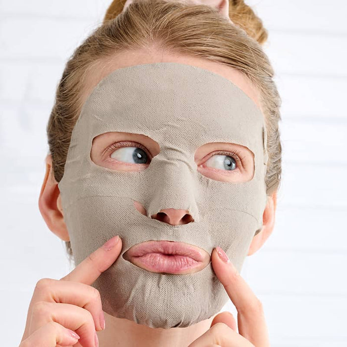 Woman wearing Patchology Mudmask Detox pressing cheeks with fingers, hydrating skincare treatment close-up