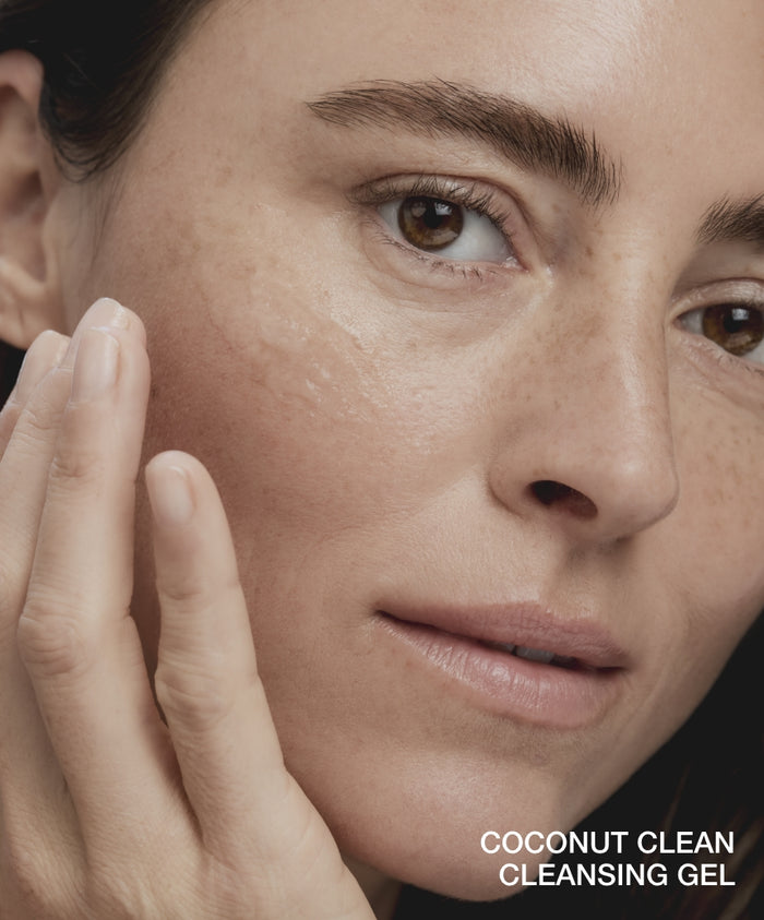 Close-up of a woman gently applying Double Clean Cleanser Duo to her cheek, showcasing natural and hydrated skin with clean beauty and skincare benefits.