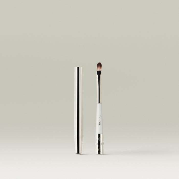 A sleek, dual-ended lip brush with a metallic cap placed beside it, showing the soft, rounded bristles and white handle with “Tropic” printed on it.