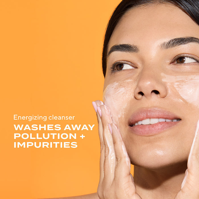 woman lathering cleanser product on face. text states energizing cleanser washes away pollution + impurities