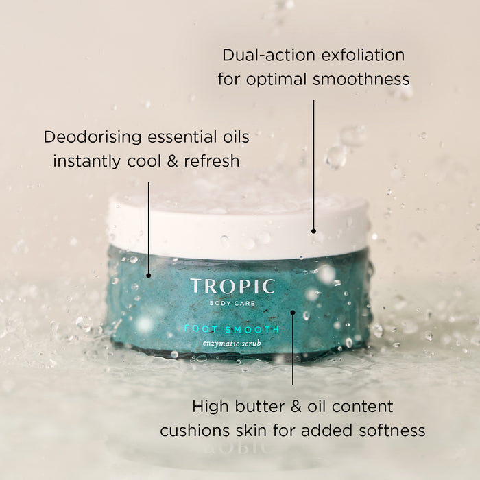 Foot Smooth Enzymatic Scrub jar in aqua glass with white lid, splashed with water droplets. Overlay text highlights: “Dual-action exfoliation for optimal smoothness”, “Deodorising essential oils instantly cool & refresh”, and “High butter & oil content cushions skin for added softness.”