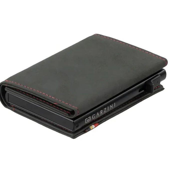 A closed GARZINI - SLIM TRIFOLD RFID-BLOCKING LEATHER WALLET WITH METAL CARD HOLDER AND COIN POCKET IN CARBON WITH RED sits beside a black "GARZINI" pen, both viewed from the side.