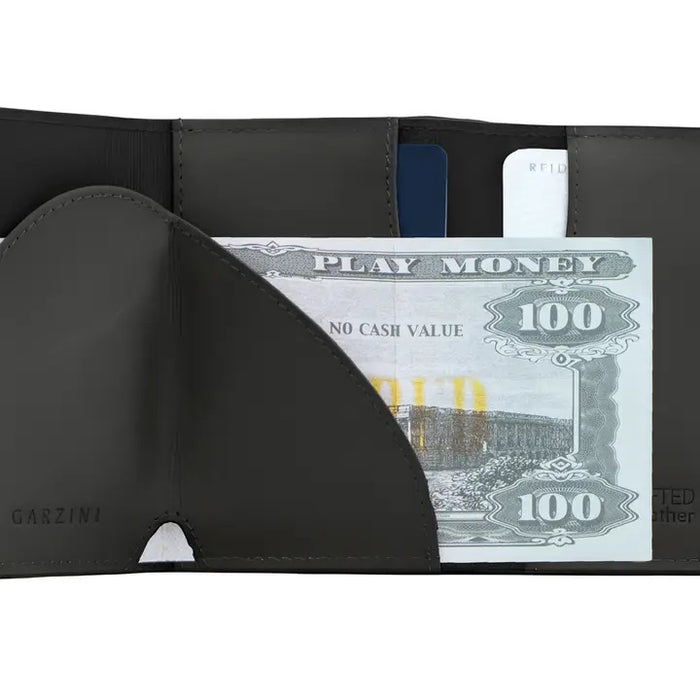 A closed black GARZINI Slim Trifold RFID-blocking leather wallet with metal card holder and coin pocket, showing the brand name on the side and cards partially visible along the edge.