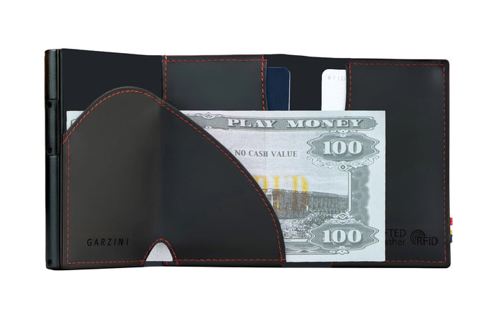 A closed GARZINI - SLIM TRIFOLD RFID-BLOCKING LEATHER WALLET WITH METAL CARD HOLDER AND COIN POCKET IN CARBON WITH RED sits beside a black "GARZINI" pen, both viewed from the side.