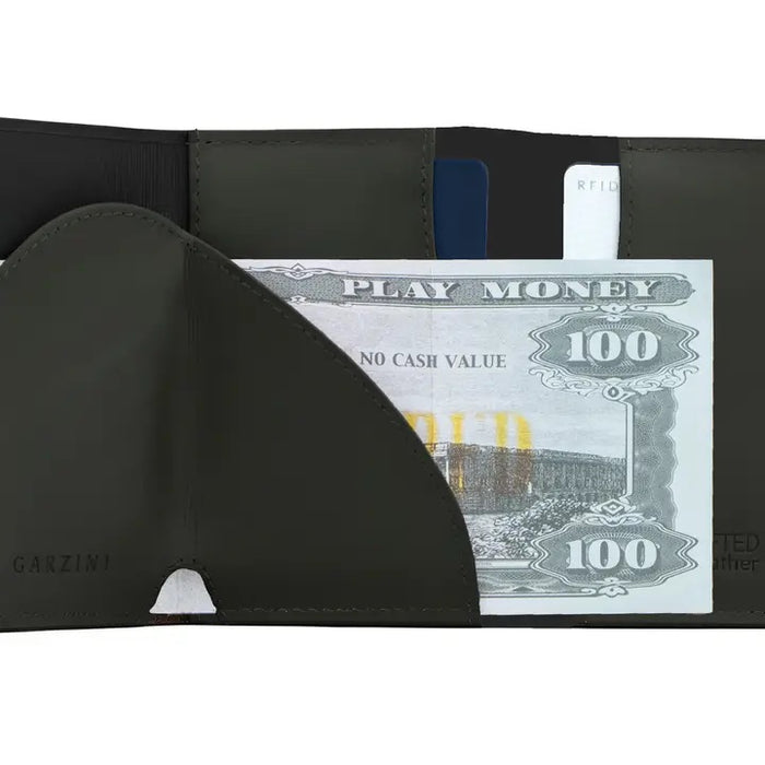 A GARZINI Slim Trifold RFID-blocking leather wallet in carbon black is shown closed, featuring a minimalist design, metal card holder, coin pocket, and the "GARZINI" logo on the side.