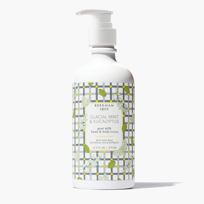 Bottle of Beekman 1802's Glacial Mint & Eucalyptus Goat Milk Lotion, designed with gingham and leaves, standing on a white background.