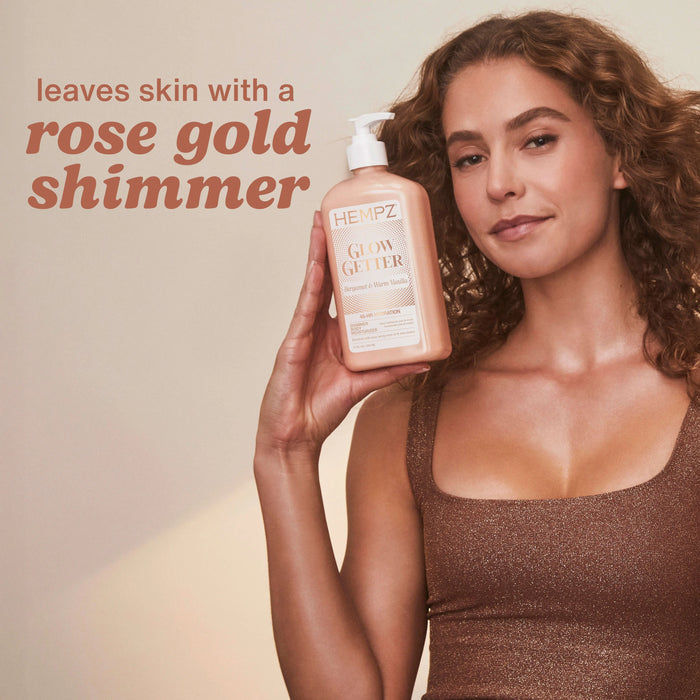 Woman holding a bottle of Hempz Glow Getter with text about rose gold shimmer on a beige background