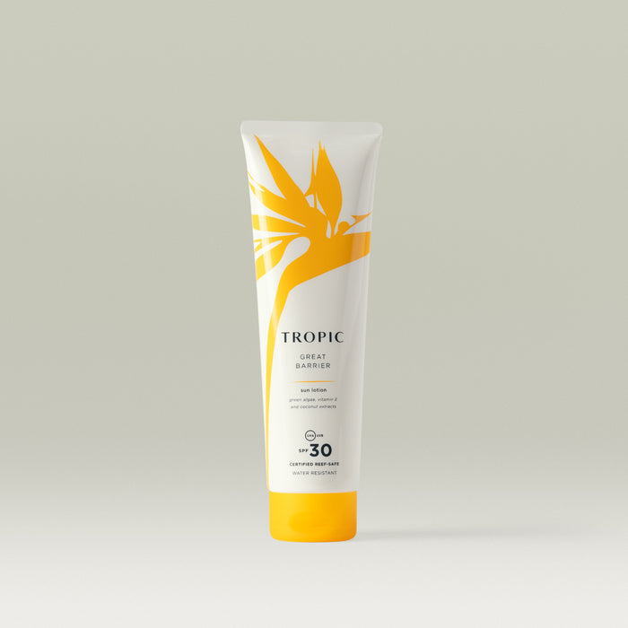 A white tube of Tropic Great Barrier Sun Lotion with SPF 30, featuring a yellow tropical leaf design and text stating 'certified reef-safe' and 'water resistant'.