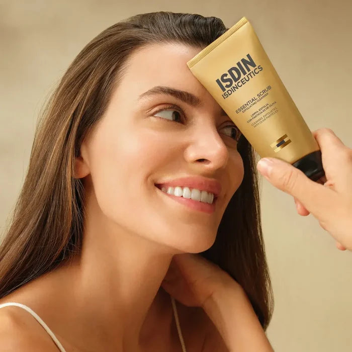 Woman applying ISDIN Essential Scrub exfoliating cleanser to her face