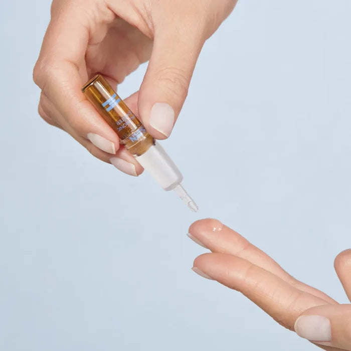 Hand applying ISDIN Isdinceutics Hyaluronic Booster ampoule serum to fingertip