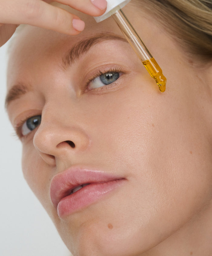 Model using RMS Kakadu Beauty Oil dropper to apply on face