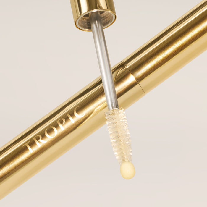 Close-up of the gold Lashful Eyelash Growth Serum showcasing its dual-ended applicator with a precision spoolie and soft cushion tip.