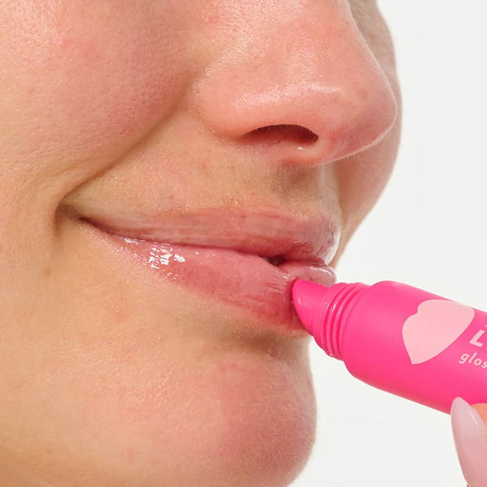 Patchology Lip Service gloss-to-balm treatment tube held in a hand for a close-up application of clear, glossy lip balm.