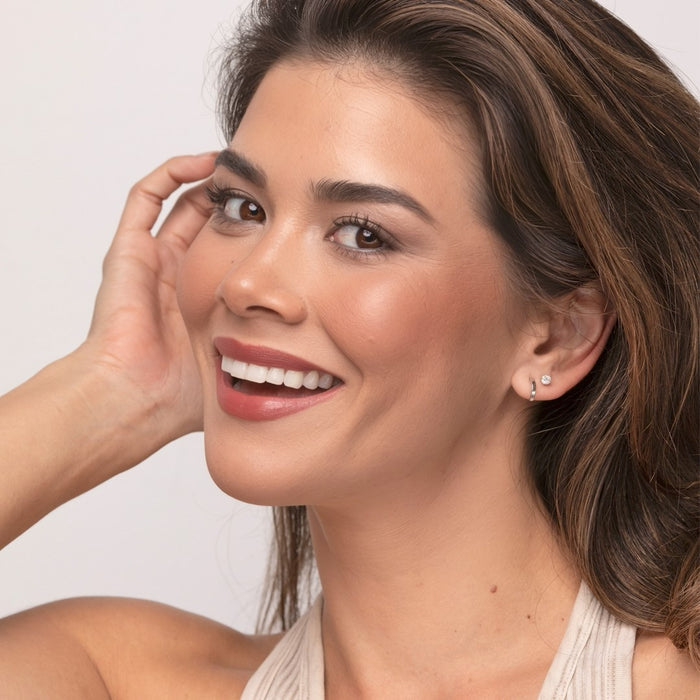 Woman with a bright smile and hand near her face wearing Demure Dark Finishing Powder.
