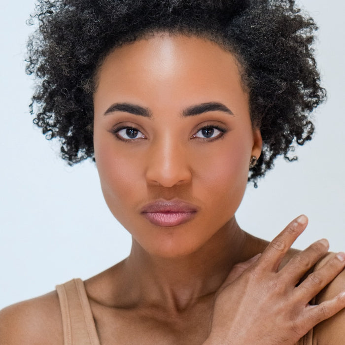 Close-up of an African American woman wearing Demure Tan Finishing Powder.