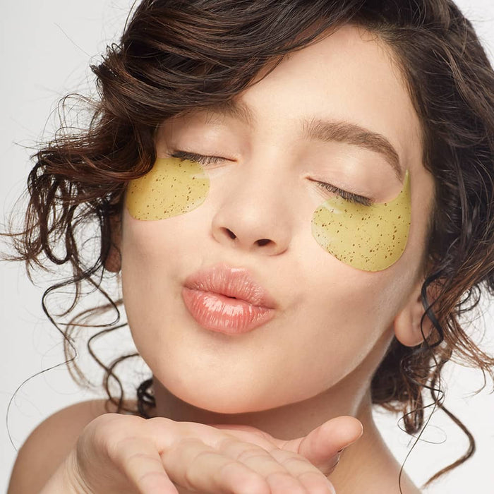 Woman wearing gold-flecked under-eye gel patches while blowing a kiss.