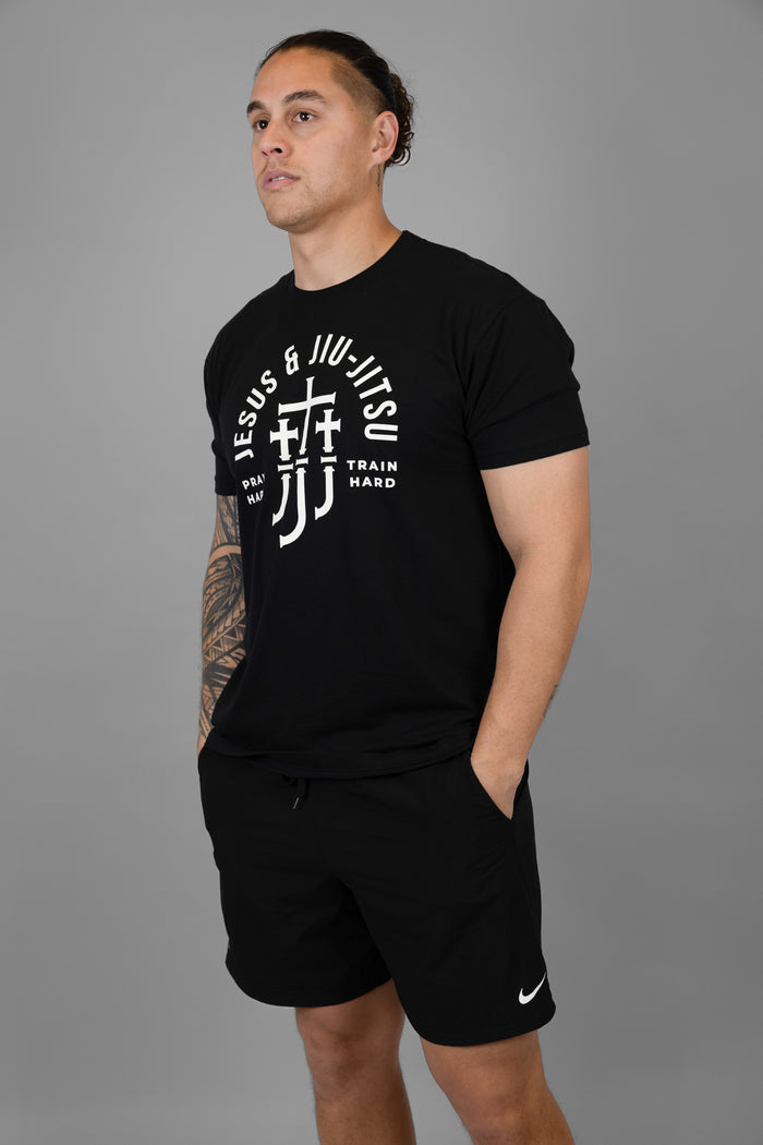 Man wearing a black t-shirt with white "JESUS & JIU-JITSU" text and logo on a gray background