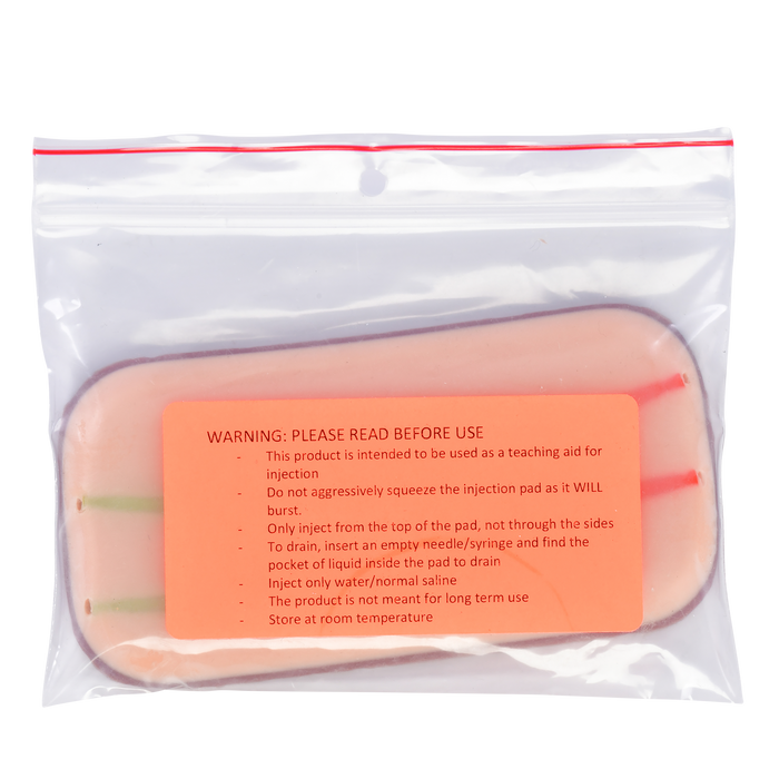 A skin-like injection pad sits inside a clear plastic bag. It is intended for teaching injection procedures. A warning label details proper usage and storage.