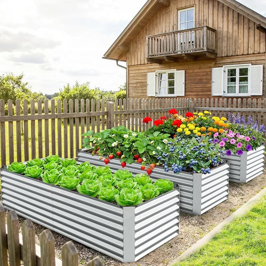 Raised garden beds with vegetables and flowers in front of a wooden house.