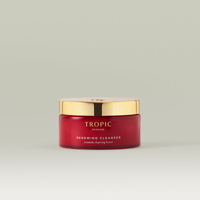 Renewing Cleanser shown in a red  jar with a gold lid, photographed on a soft neutral background.