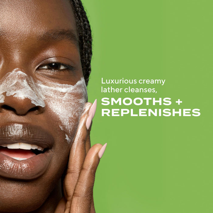 woman lathering product on face with text stating luxurious creamy lather cleansers, smooths + replenishes on green background