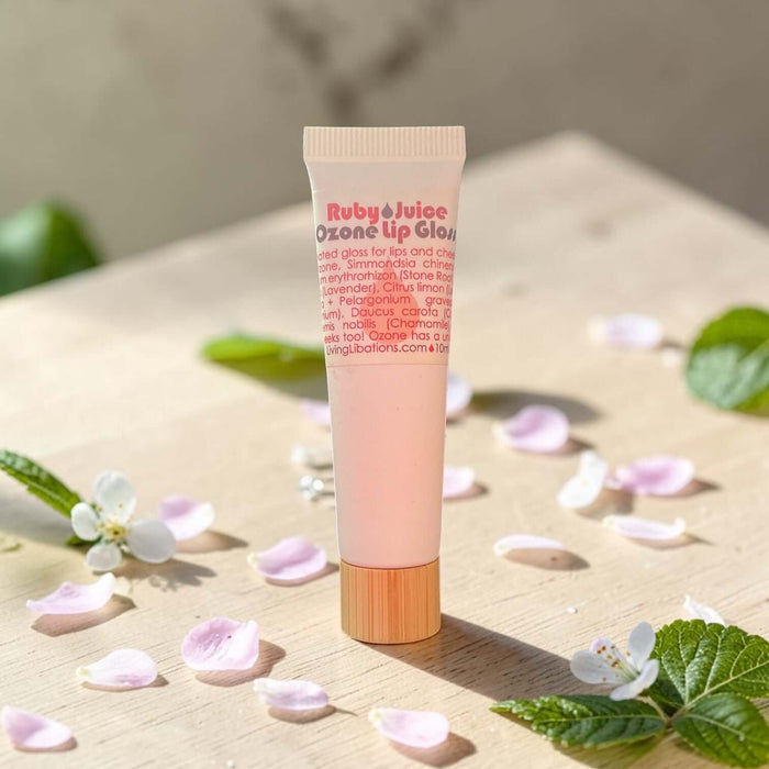 Tube of Ruby Juice lip gloss on a wooden surface with flowers and leaves