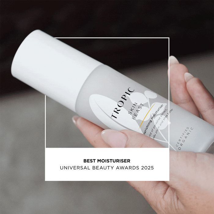 A person holding a white bottle of Tropic Skin Feast Nourishing Moisturiser. The text overlay says, “Best Moisturiser – Universal Beauty Awards 2025. A verified buyer quotes: "Wouldn't use anything else! Best moisturiser I have ever used." Lasma H five star review and verified customer.