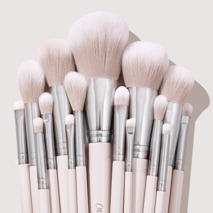 Stone Cold ColourPop Makeup Brush Kit fanned upright, displaying powder, blush, contour, and eye brushes with fluffy blush-pink bristles, silver ferrules, and pale pink handles, stacked tightly against a soft beige backdrop.