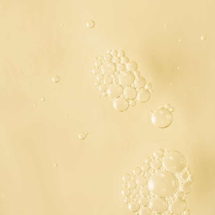 Close-up texture image of golden liquid bubbles suspended against a soft cream background.
