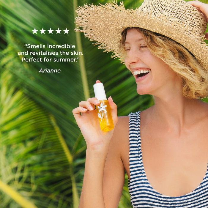 Person holding Tropic Summer Spritz Refreshing Facial Mist with five-star customer review: "Smells incredible and revitalises the skin. Perfect for summer." – Arianne.