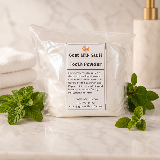 Packaged goat milk tooth powder with mint leaves on a bathroom counter