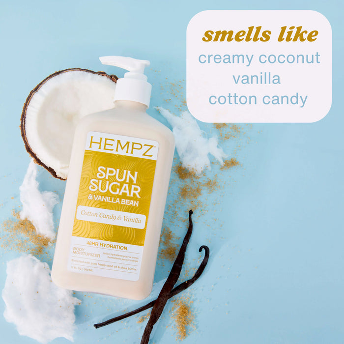 Hempz Spun Sugar & Vanilla Bean bottle with coconut, vanilla bean, and cotton candy on a light blue background