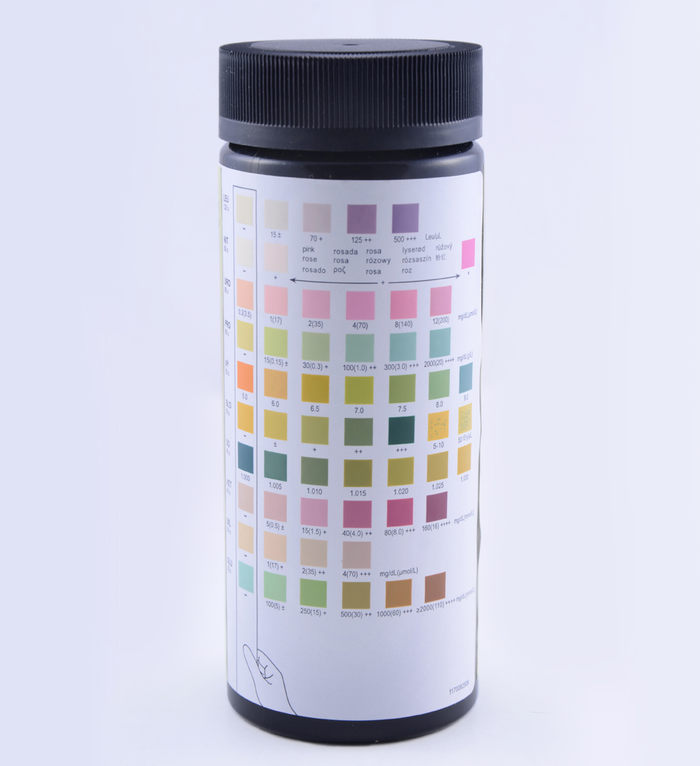 A cylindrical bottle displays a color chart; it shows various color gradients for comparison against a urine sample; the bottle is set against a white background.