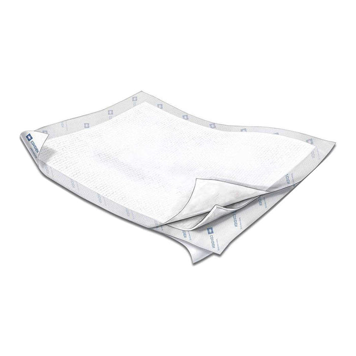 Two white, square medical pads are shown slightly stacked, with one corner of the top pad lifted to expose the bottom pad. "COVIDIEN" is printed on the edge of the pads. The pads are on a white surface.