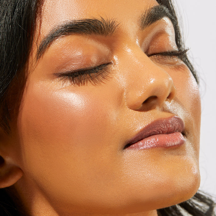 A close-up of a woman with smooth, glowing skin and glossy lips in natural light highlights the radiant complexion achieved using the BOOtiful Skin Bundle.